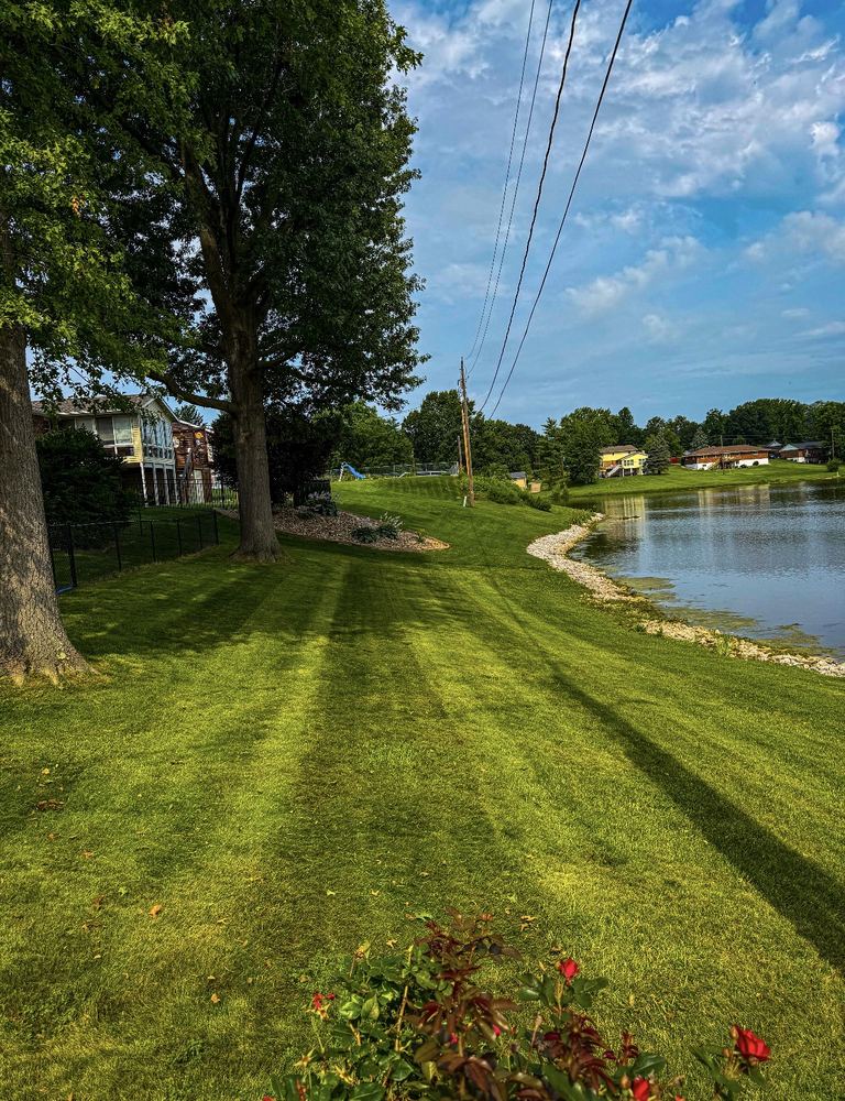 Striped mowed backyard lawn along the pond at sunset