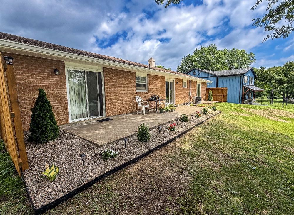 Brick home backyard patio with new landscape bed and rock border
